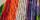 Multi-coloured origami cranes strung together vertically and hung on a wall.